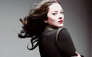 Marion Cotillard stands side-ways in captivating elegance.