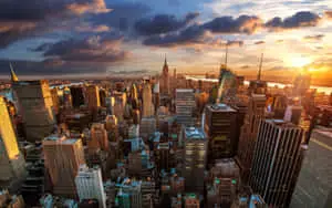 a cityscape with buildings and clouds at sunset
