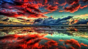 a colorful sunset with clouds reflected in the water