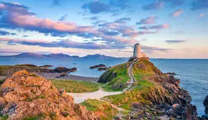 a lighthouse sits on top of a rocky cliff