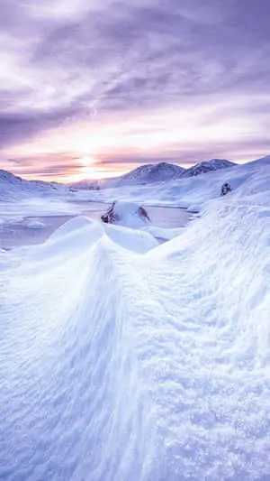 a snow covered landscape with a sunset