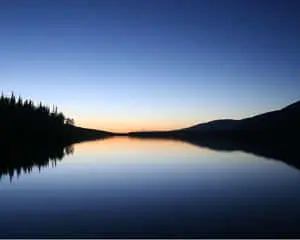 Serene nature landscape with mountain, lake, and bright blue sky